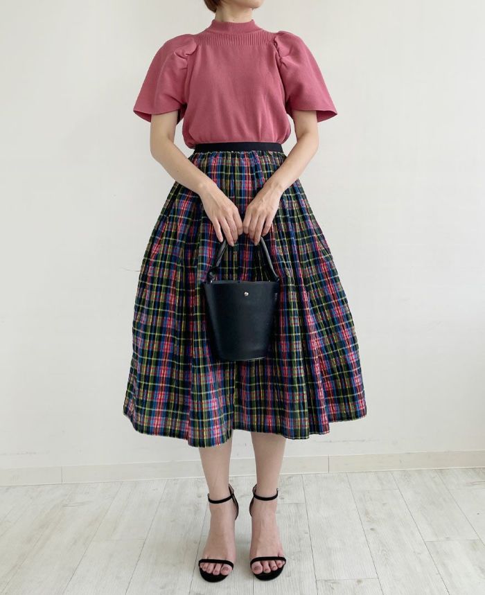 鮮やかなカラーのチェック柄スカートとピンクが相まって華やかなコーディネートに。