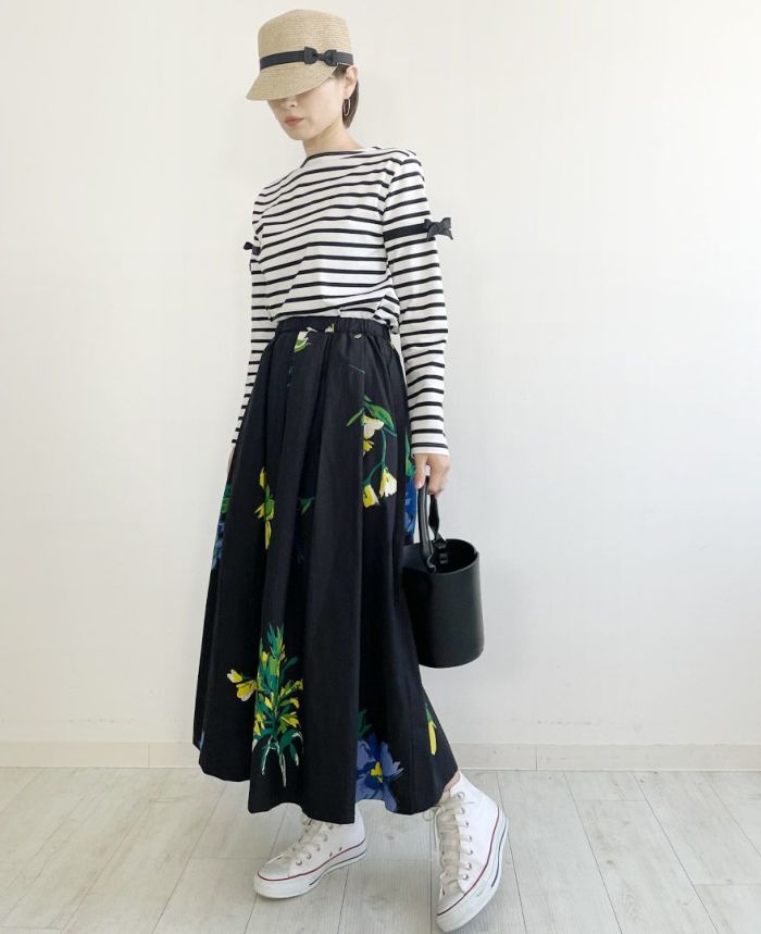 黒ベースに黄色や水色のお花がプリントされたフレアスカートにボーだートップスとスニーカーを合わせた大人のお出かけスタイルコーデ