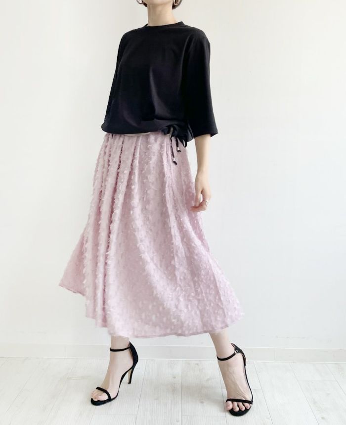 裾を絞った黒のトップスにピンクのスカートを合わせたコーデ。
