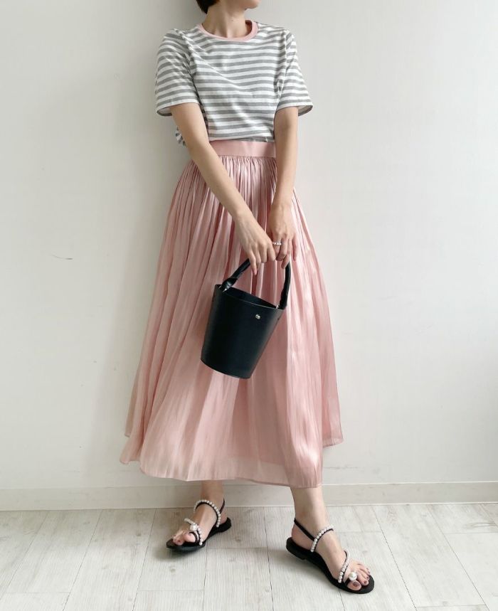 光沢感のあるピンクのスカートにTRECODE（トレコード）のバイカラーTシャツのパイピングのピンクが相まって柔らかい印象に。