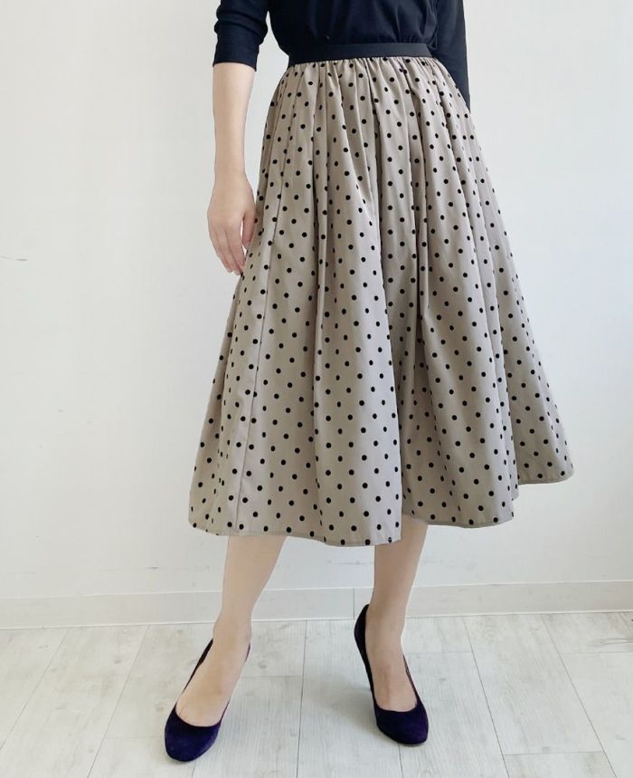 落ち着いたベージュにベルベットのような質感の大きすぎない黒のドット柄が施されているフレアスカート
