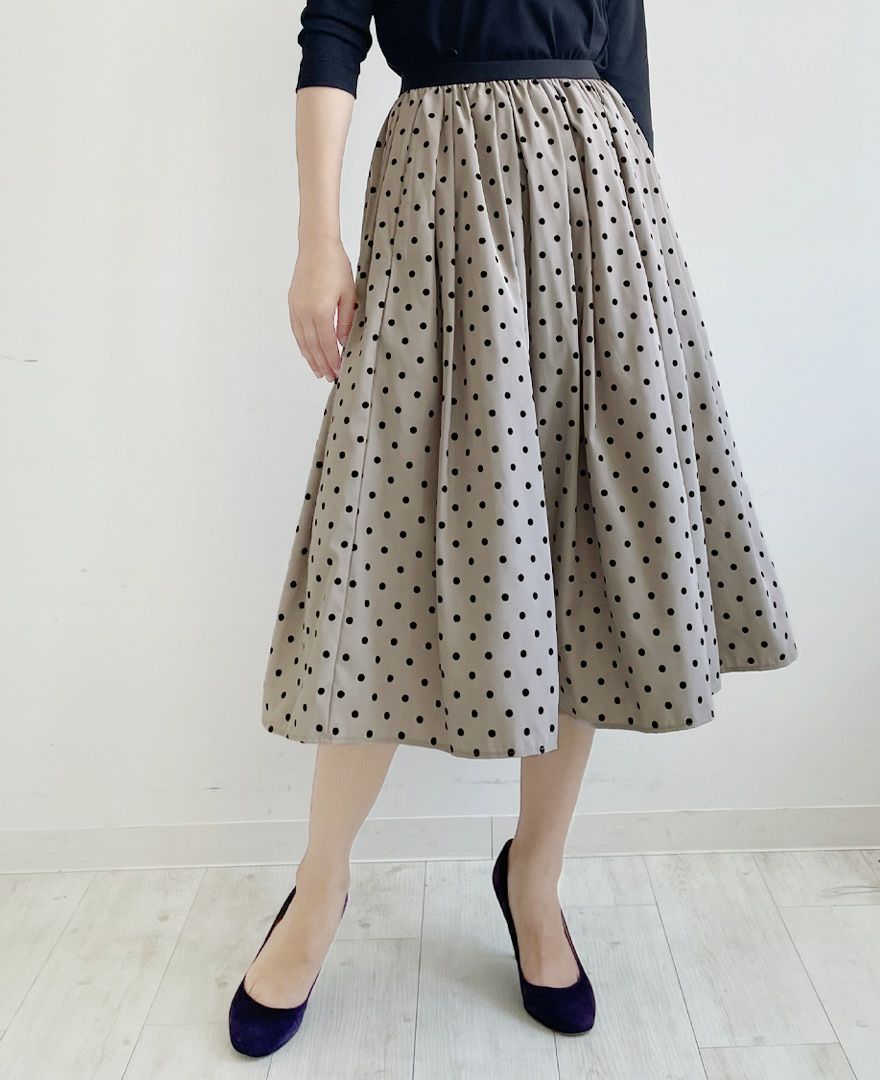 落ち着いたベージュにベルベットのような質感の大きすぎない黒のドット柄が施されているフレアスカート