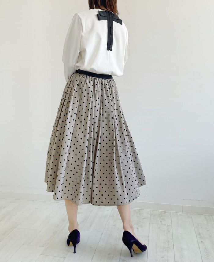 後ろにリボンが付いた白のトップスをインして女性らしい柔らかい印象のコーディネート