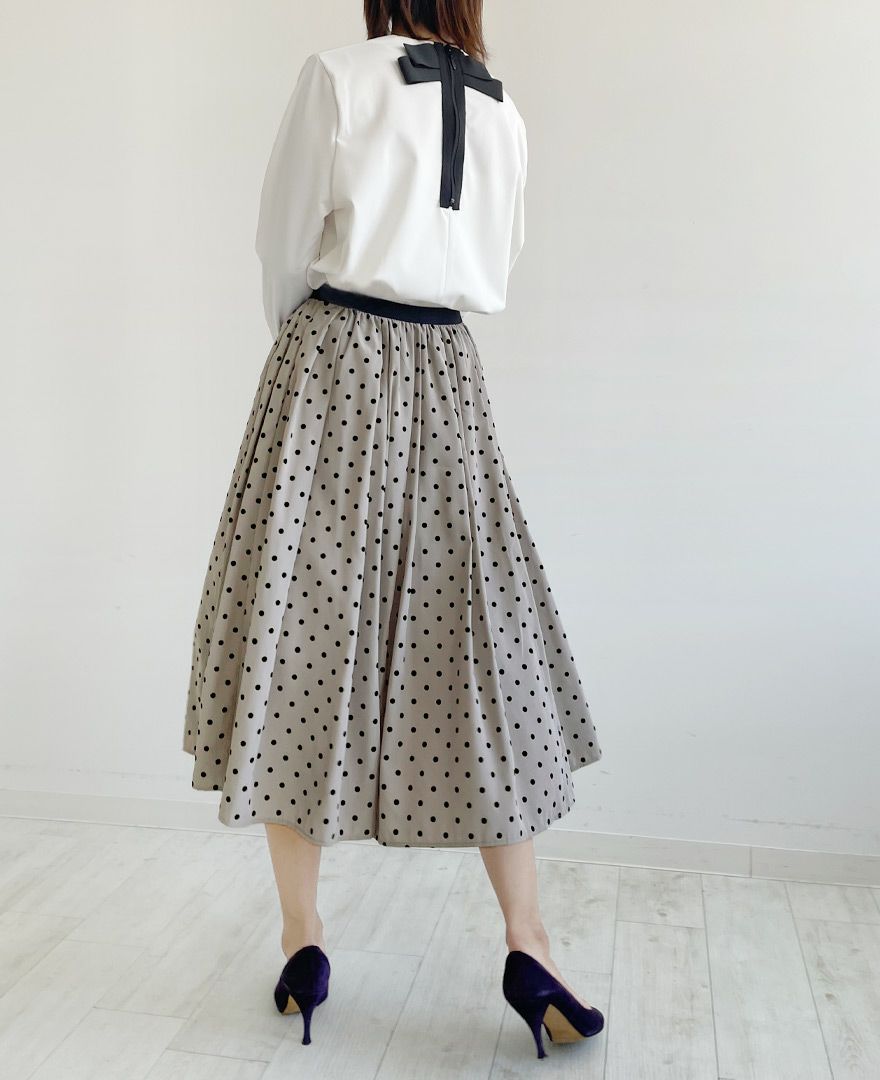 後ろにリボンが付いた白のトップスをインして女性らしい柔らかい印象のコーディネート