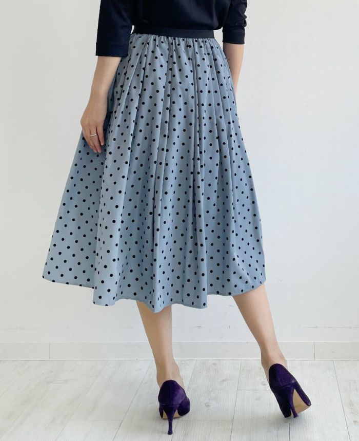 くすみがかったブルーにベルベットのような質感の大きすぎない黒のドット柄が施されているフレアスカート