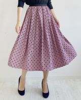 くすみがかったピンクにベルベットのような質感の大きすぎない黒のドット柄が施されているフレアスカート