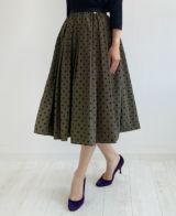ブラウン味を帯びたカーキにベルベットのような質感の大きすぎない黒のドット柄が施されているフレアスカート