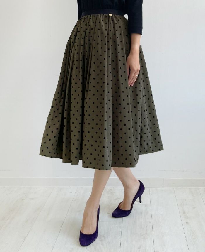 ブラウン味を帯びたカーキにベルベットのような質感の大きすぎない黒のドット柄が施されているフレアスカート