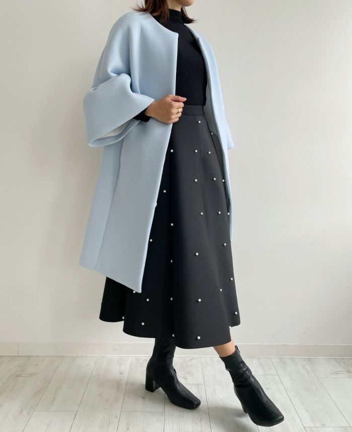 ブラックのスカートと柔らかい色味のブルーの組み合わせが女性らしいスタイリング