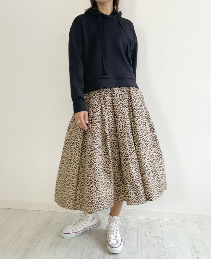 ピンクのフレアスカートとTRECODE（トレコード）のバックフリルフードプルオーバーブラックを合わせて大人フェミニンなコーディネートに。