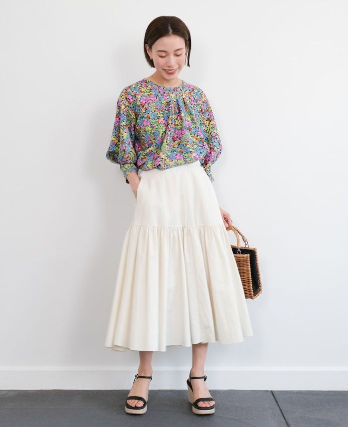 花柄ブラウスのピンクにホワイトのスカートとブラックのサンダルとカゴバッグを合わせたコーディネート