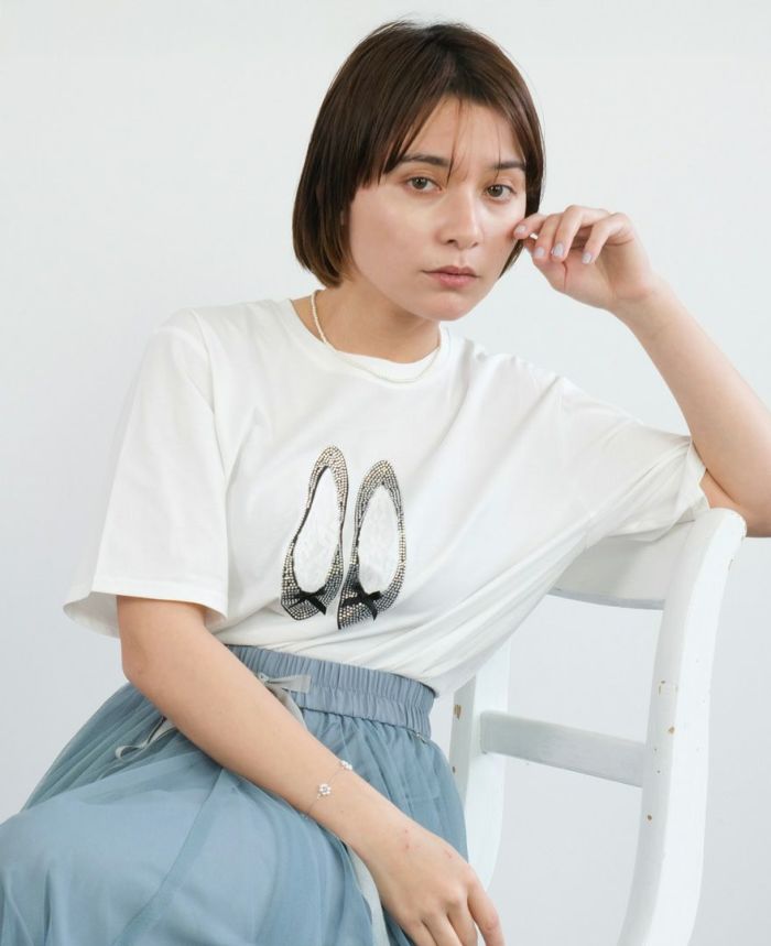 バレエシューズモチーフTシャツの白にブルーのスカートを合わせて椅子に座った写真