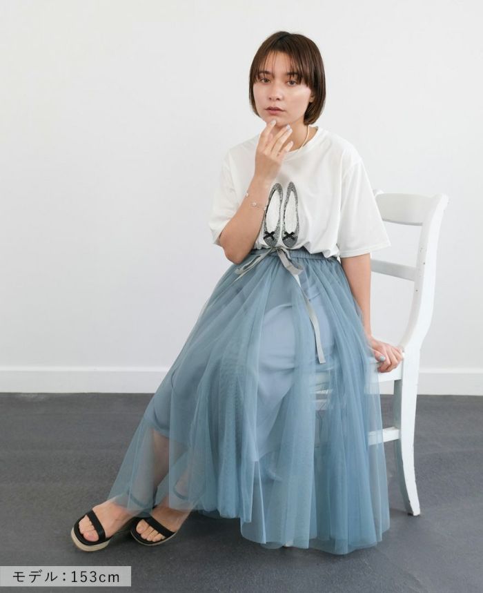 バレエシューズモチーフTシャツの白にブルーのスカートを合わせて椅子に座った写真