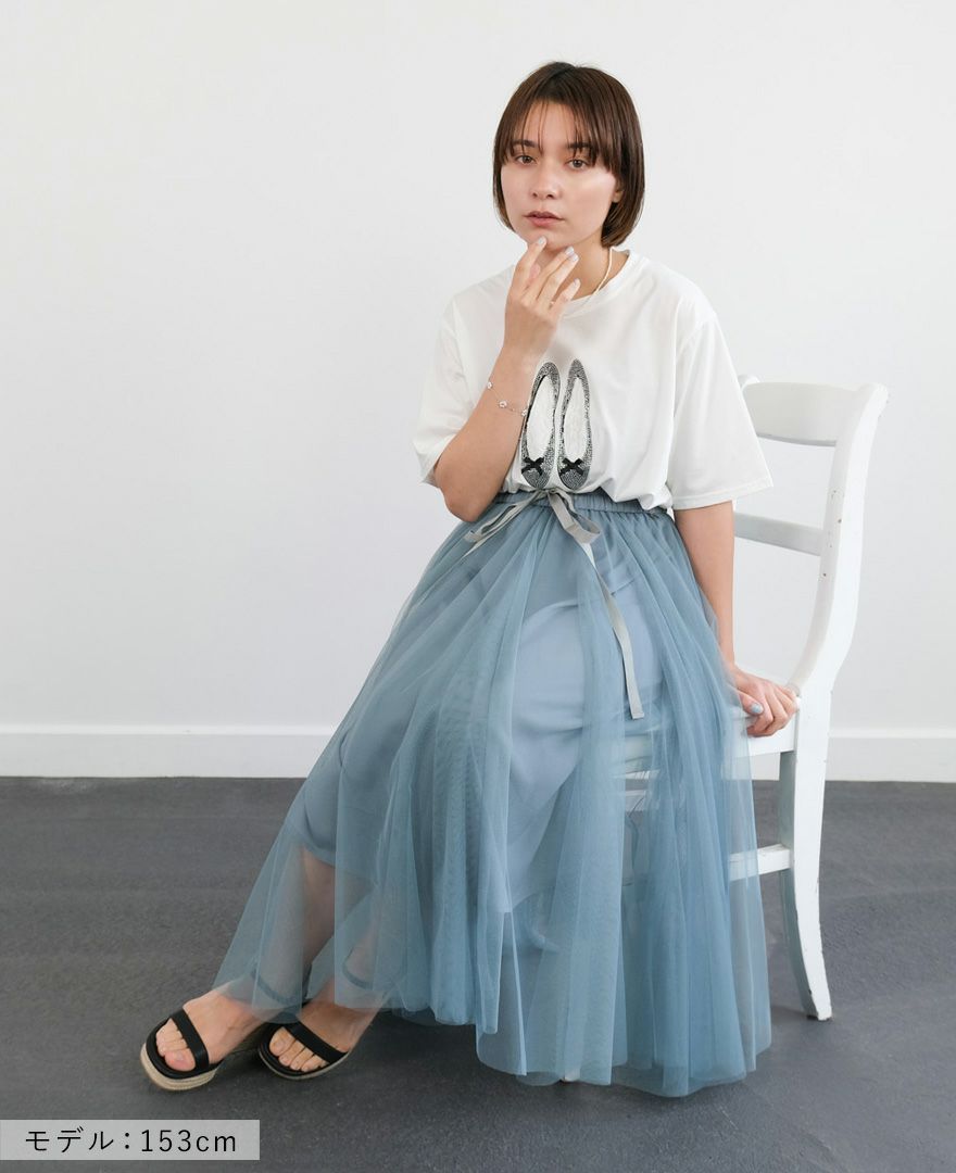 バレエシューズモチーフTシャツの白にブルーのスカートを合わせて椅子に座った写真