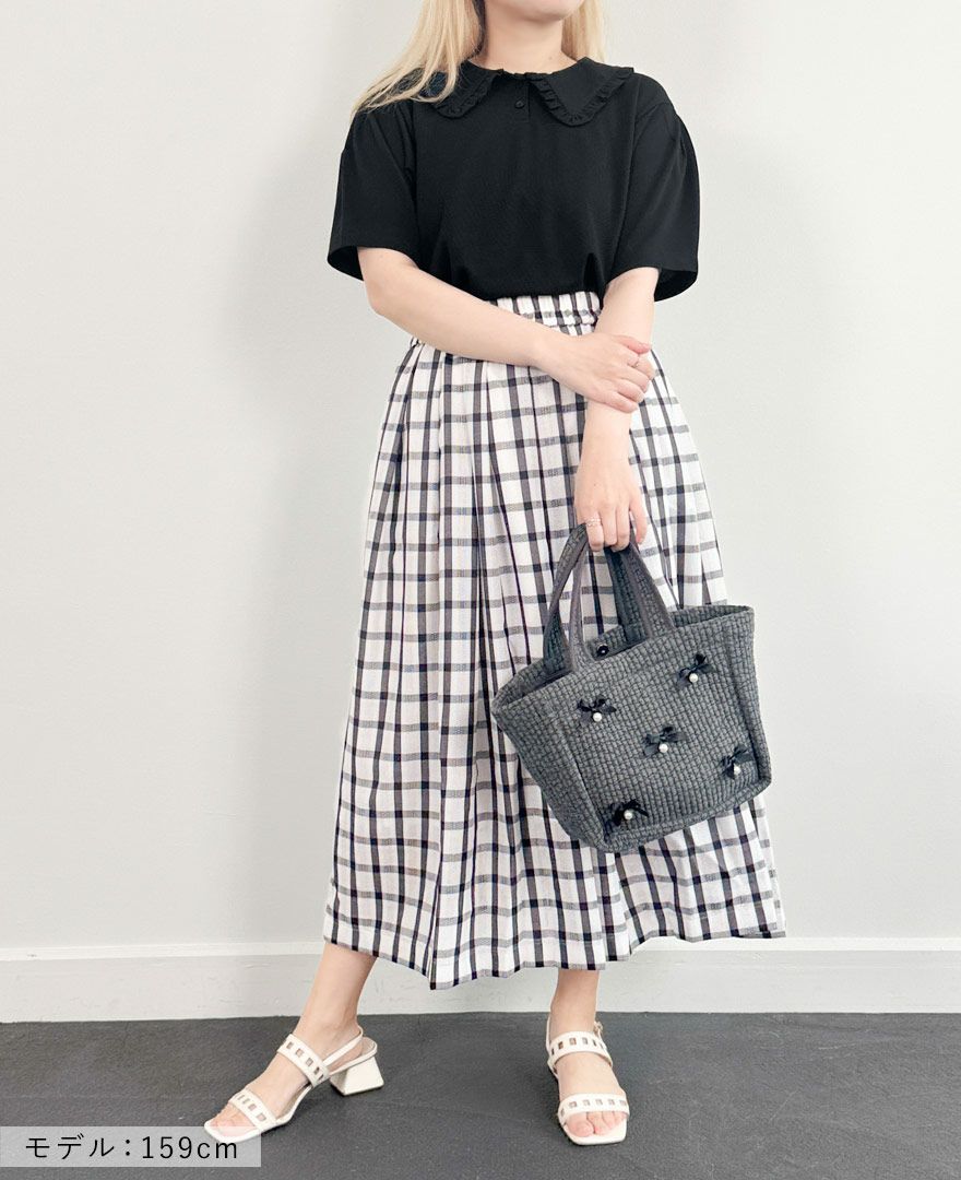 ブラックのカノコポロシャツにネイビーのチェックスカートとグレーのヌピバッグを合わせたコーディネート
